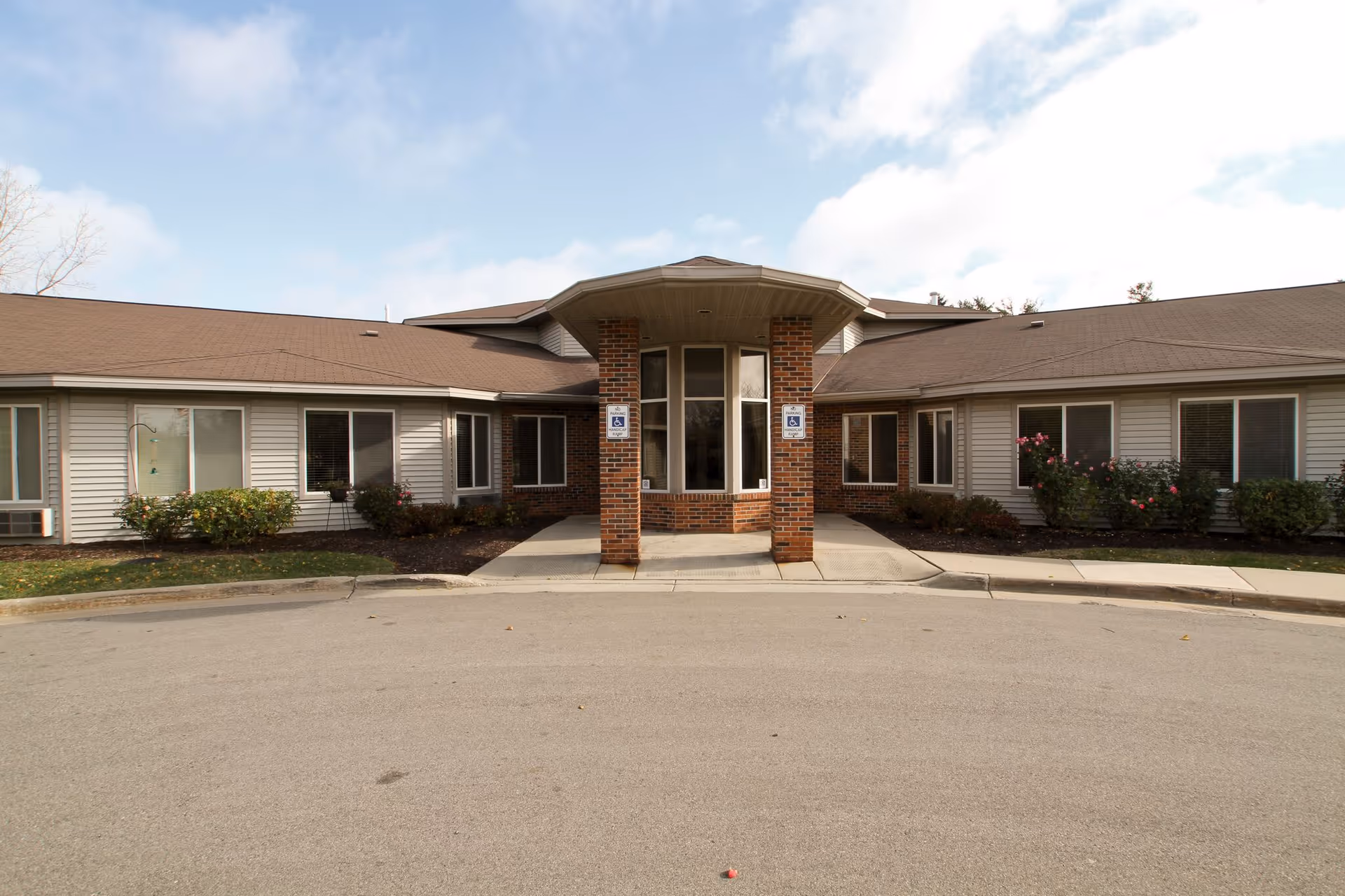 Exterior view of a single-story senior living facility entrance with brick columns.