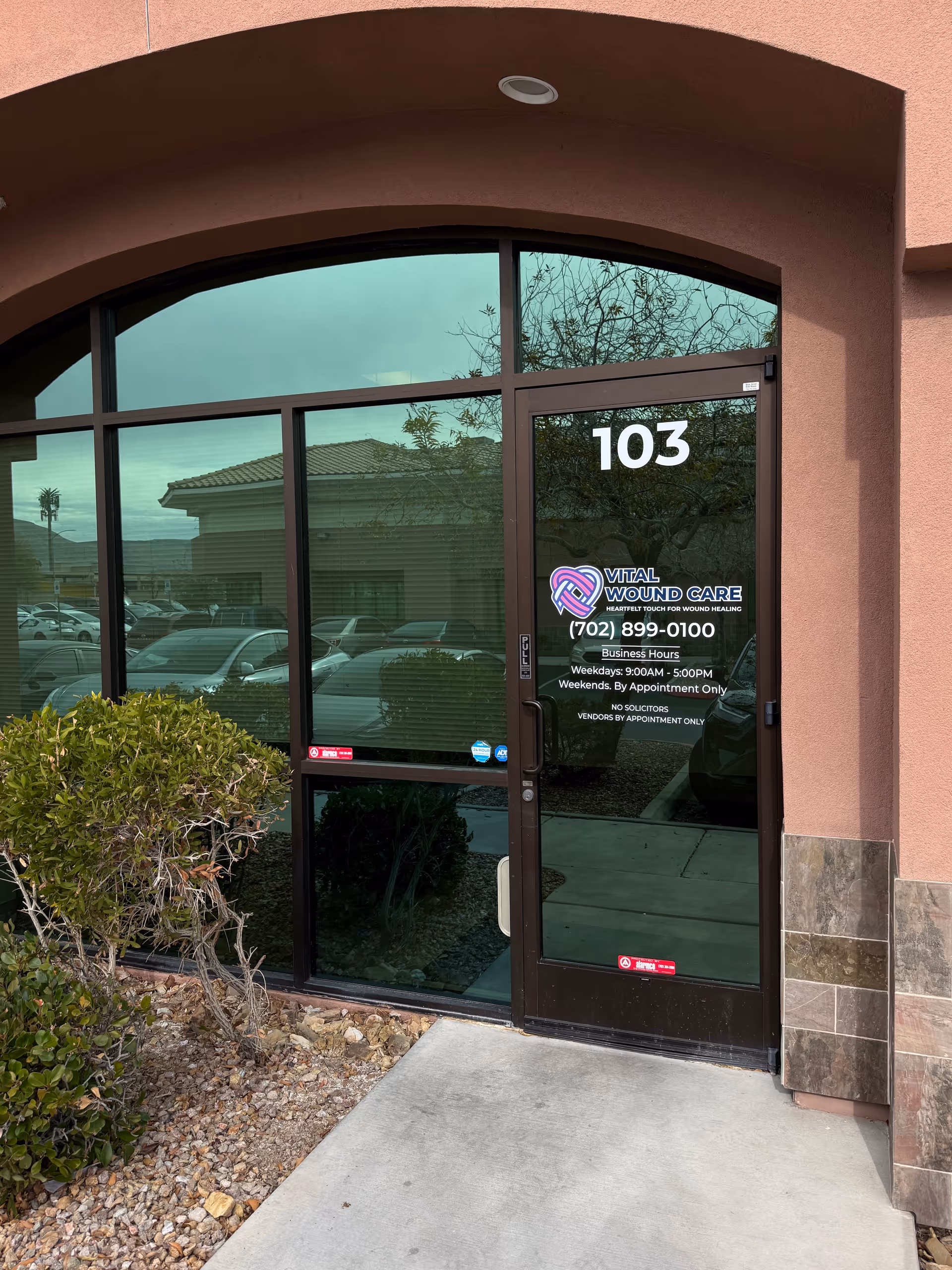 Exterior entrance of Vital Wound Care with glass doors and 103 address.
