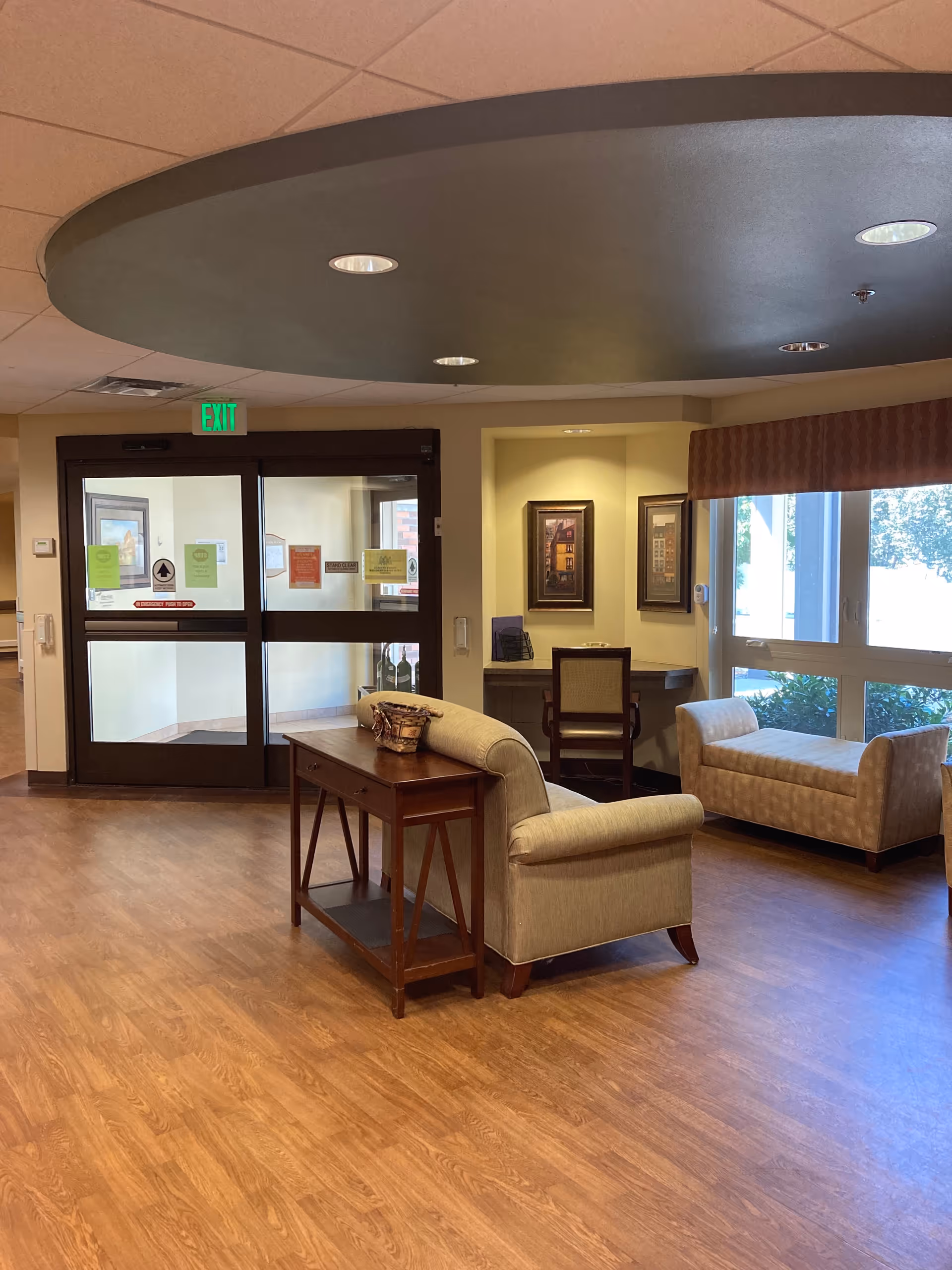 Senior living facility lobby with beige seating, a console table, and glass exit doors.