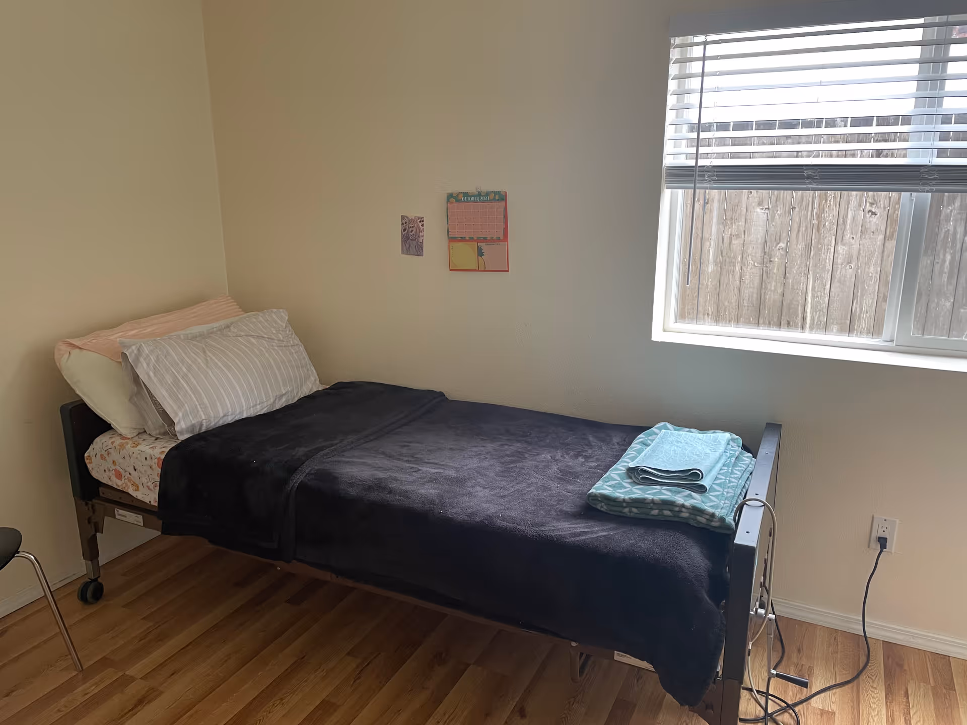 A single bed with pillows in a small, sunlit bedroom at a care home