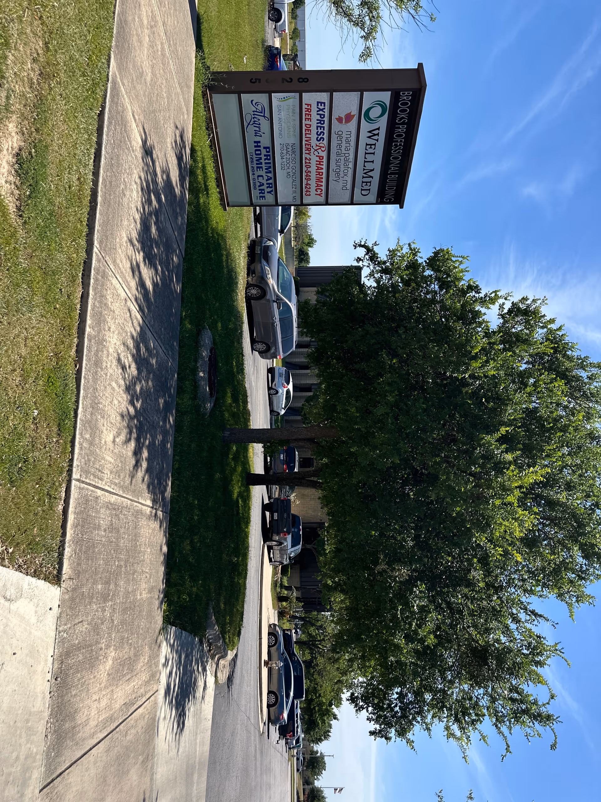 Exterior of a building with a tall sign and parked cars.