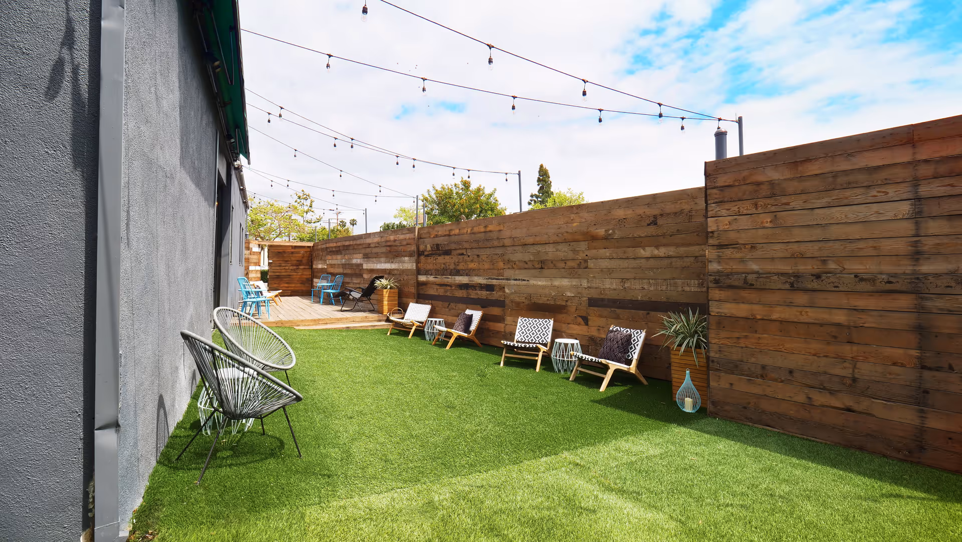 Private outdoor patio with string lights, seating, and privacy fence.