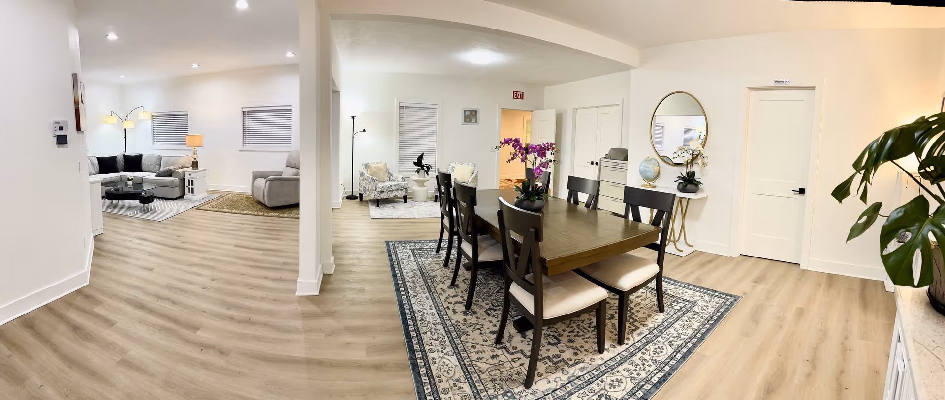 Bright open interior with a wooden dining table, chairs, and living areas in a senior home.
