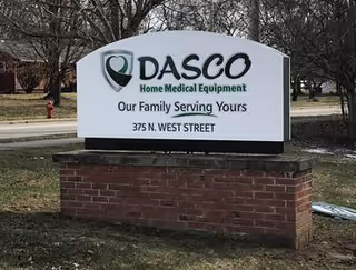 A DASCO sign for Home Medical Equipment at the administrative office mounted on a brick pedestal.