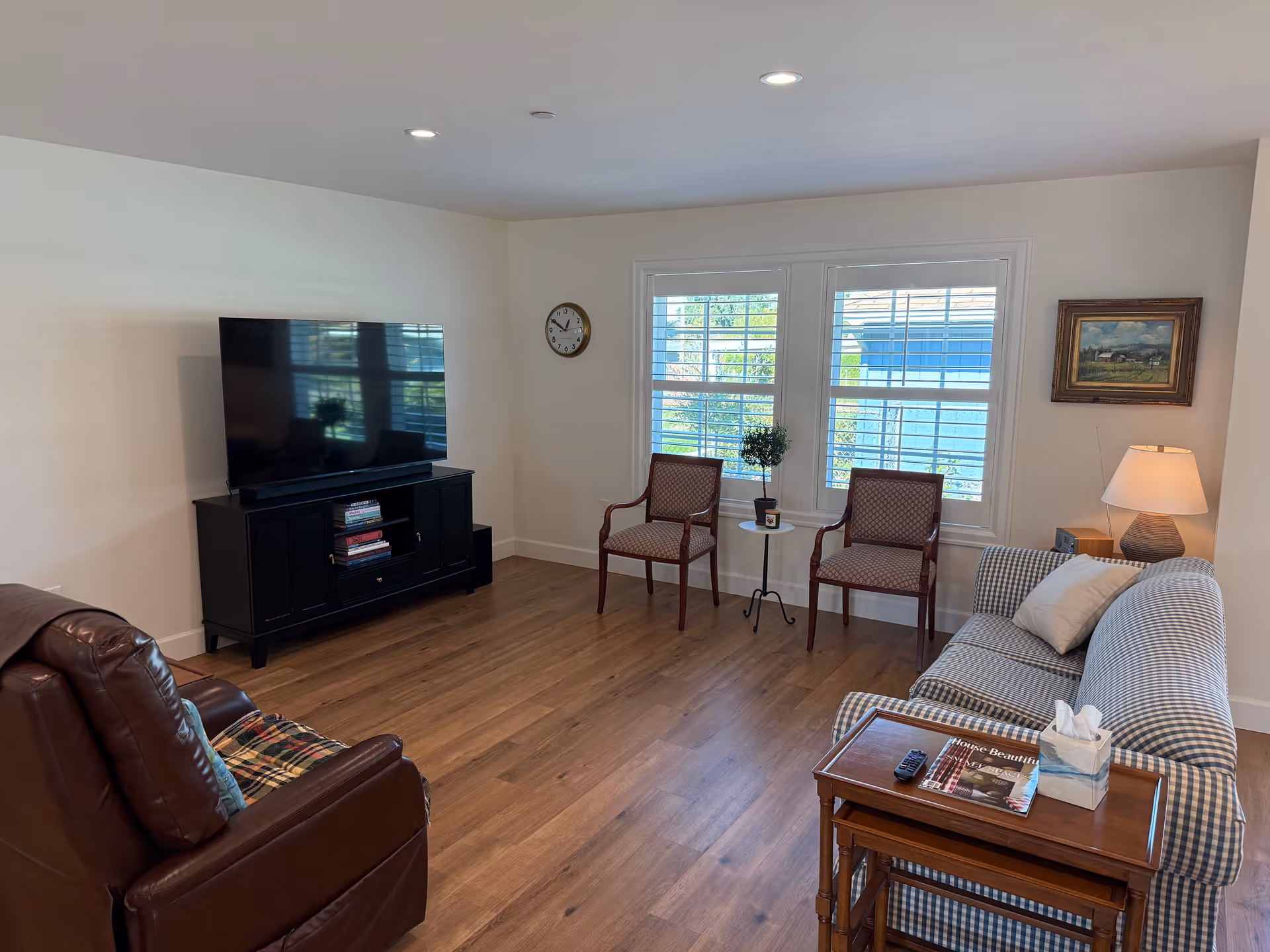 Bright living room with TV, two chairs, couch, window light, and a side table.
