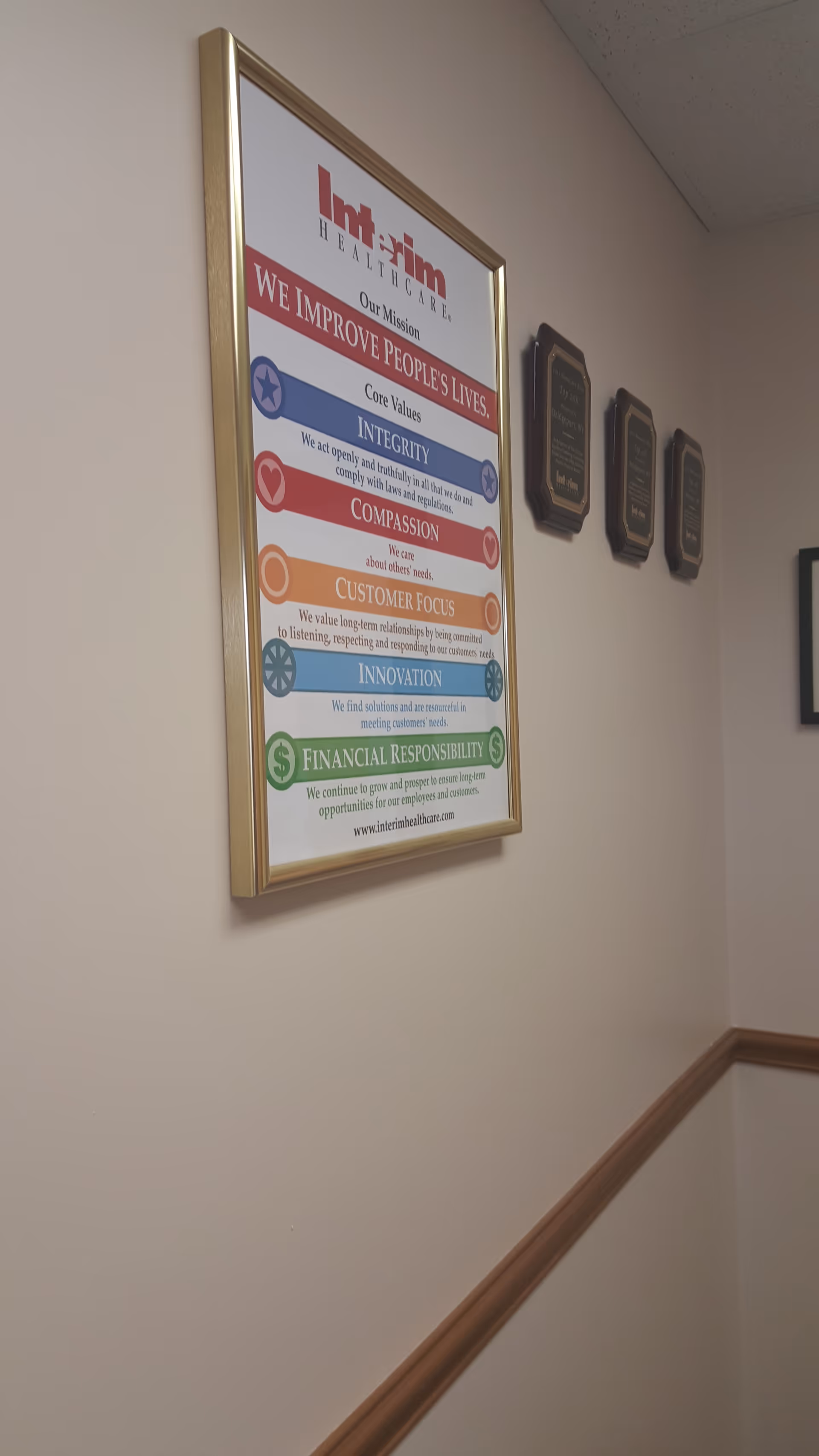 Interior hallway with a framed mission poster and wall plaques in a care facility.