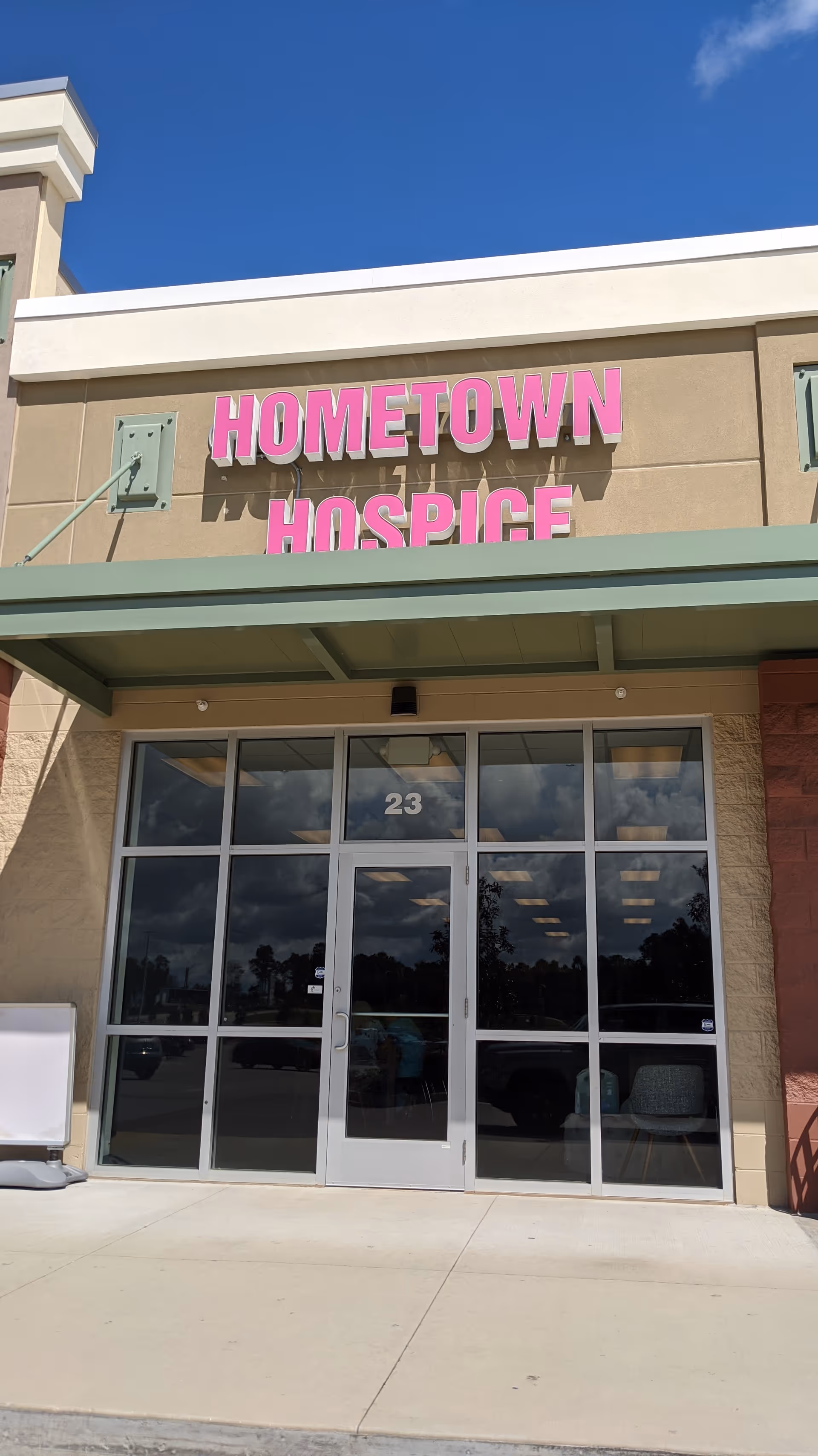 Exterior view of a building entrance with a pink Hometown Hospice sign.