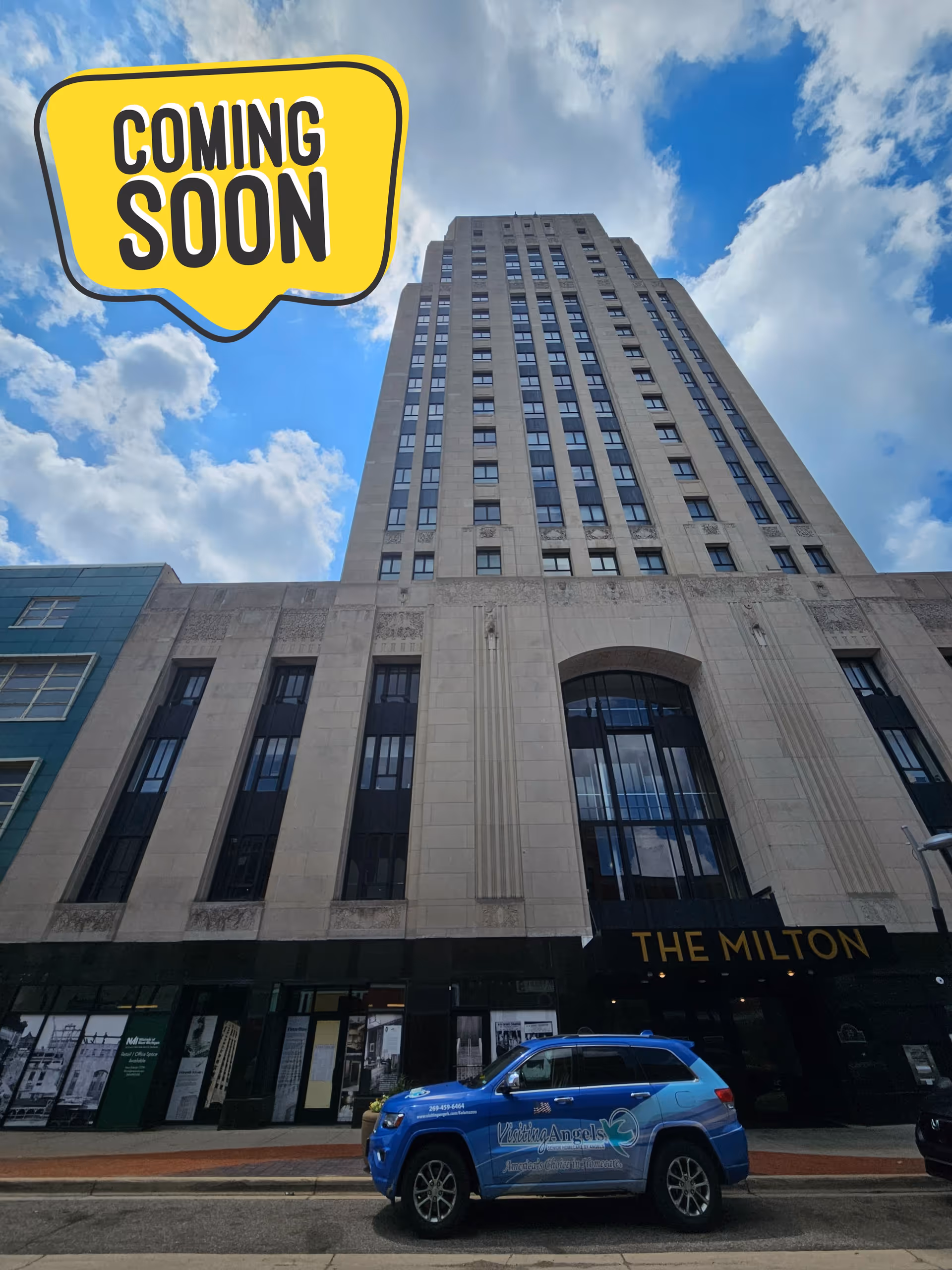 Tall city building with a blue Visiting Angels vehicle parked outside; Coming Soon sign.