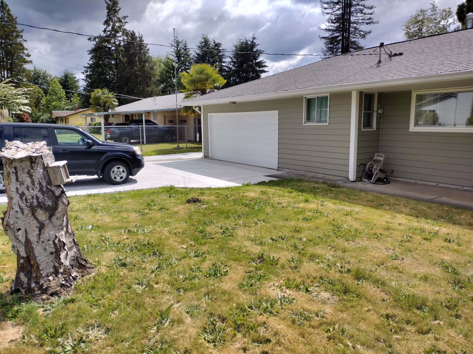 Front view of a single-story residence with a closed garage, driveway, and yard.