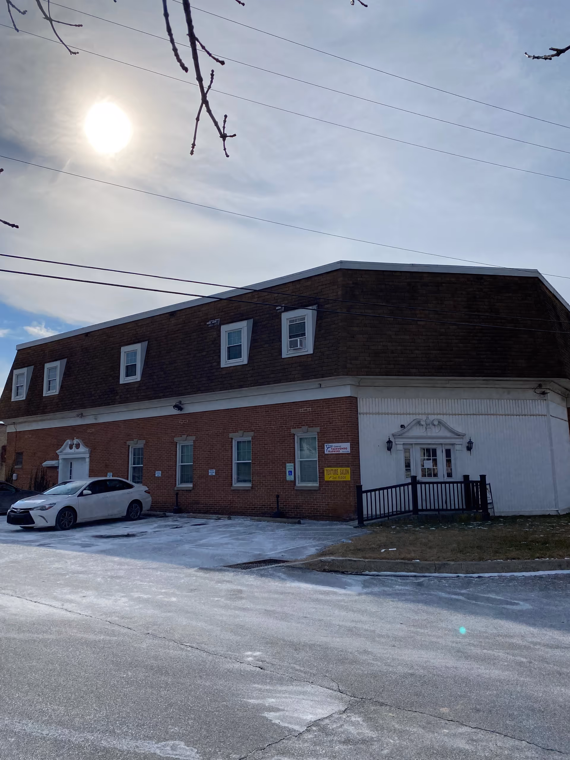 Exterior view of a brick senior care facility with white doors and a parked car.