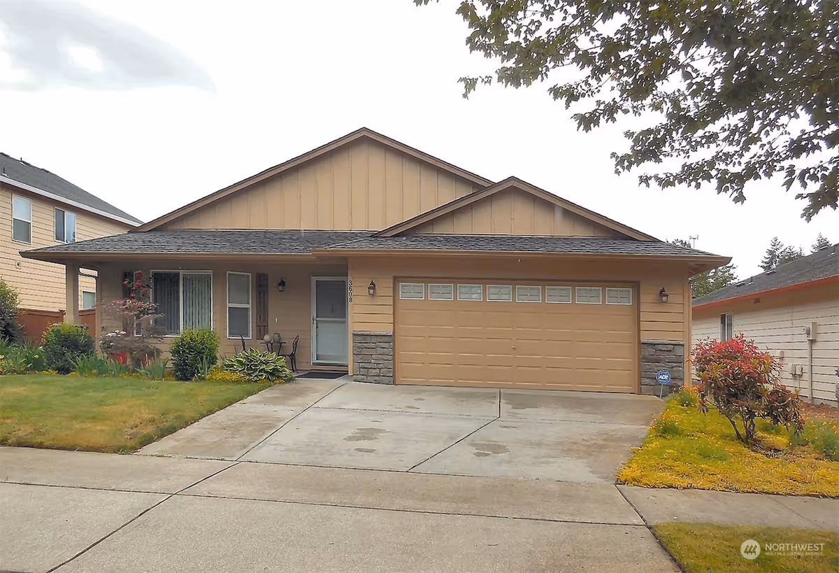 Residential-style house with a tan attached garage and manicured front lawn.