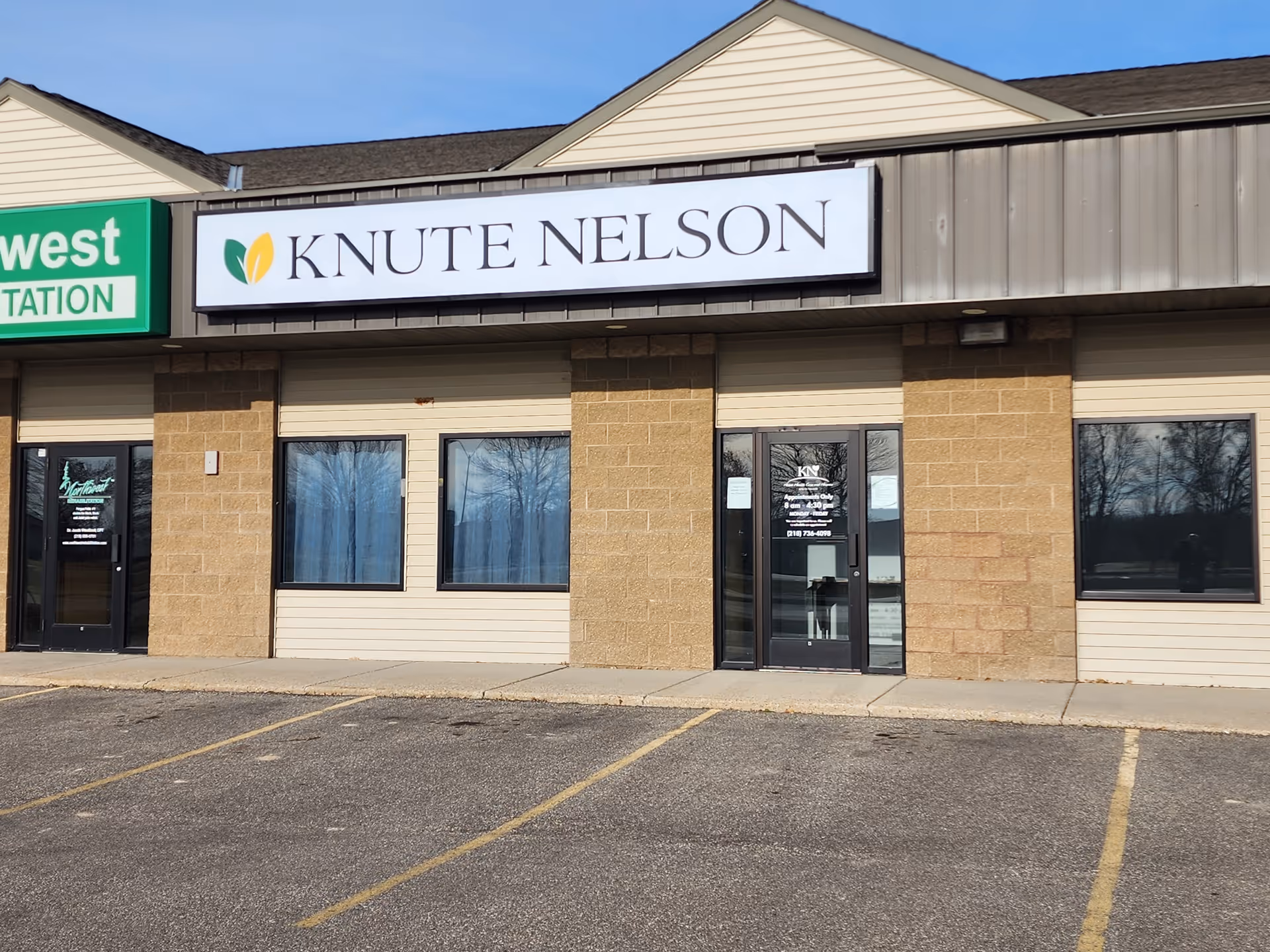 Exterior storefront of Knute Nelson facility with signage and parking lot in front