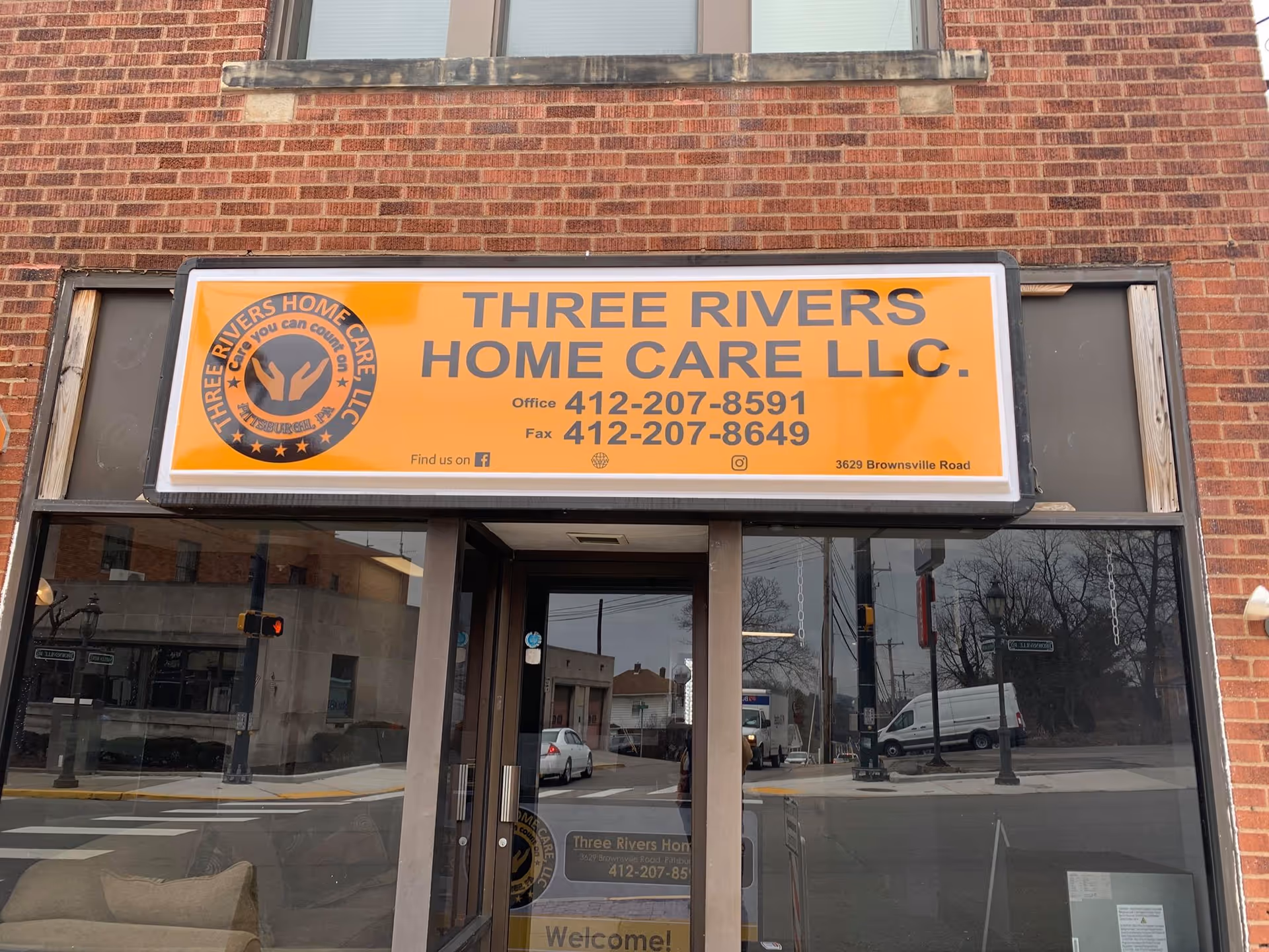Brick storefront with a large orange Three Rivers Home Care LLC sign above the entrance