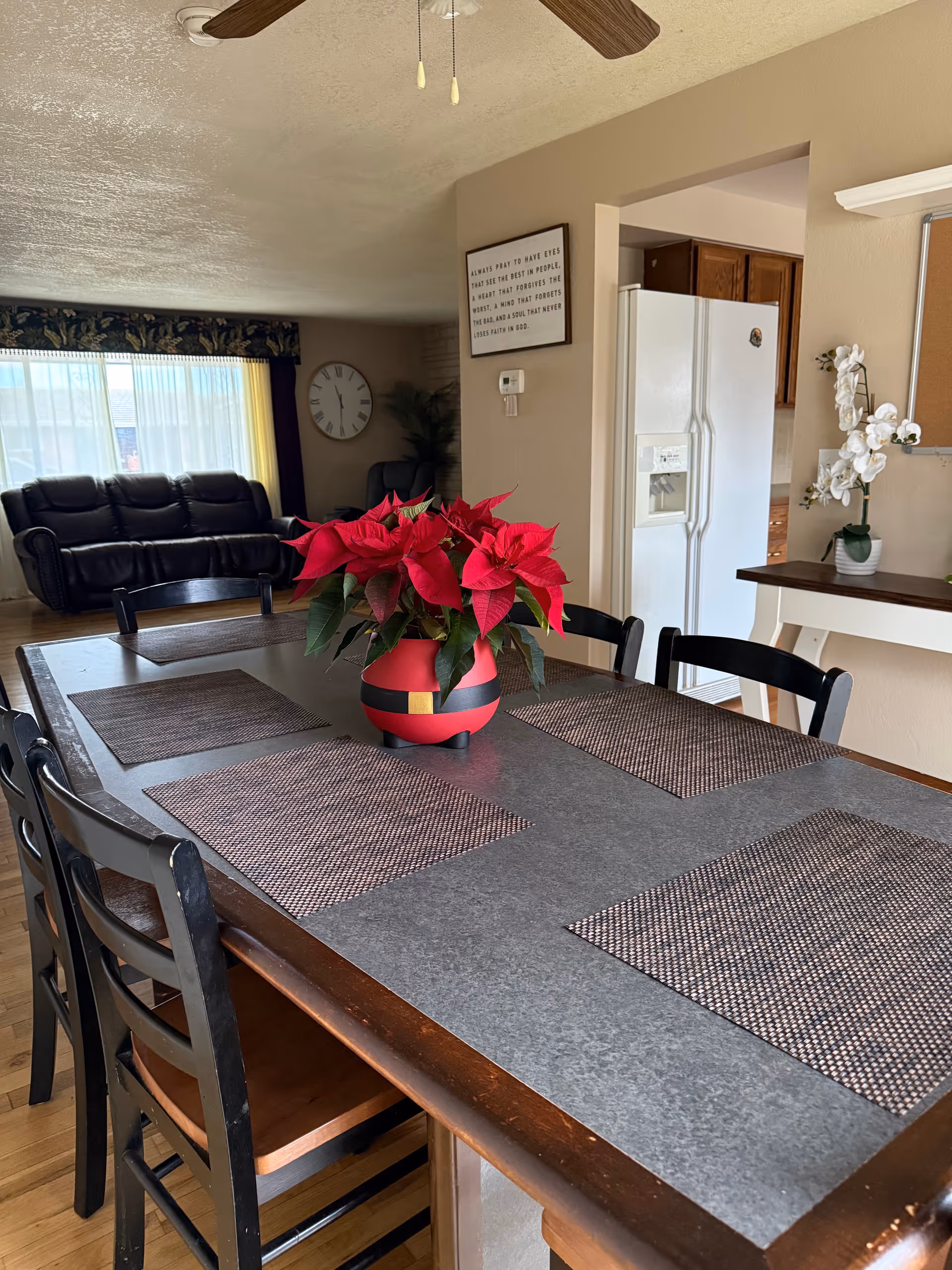 Dining table with a red poinsettia centerpiece in a cozy open living area.