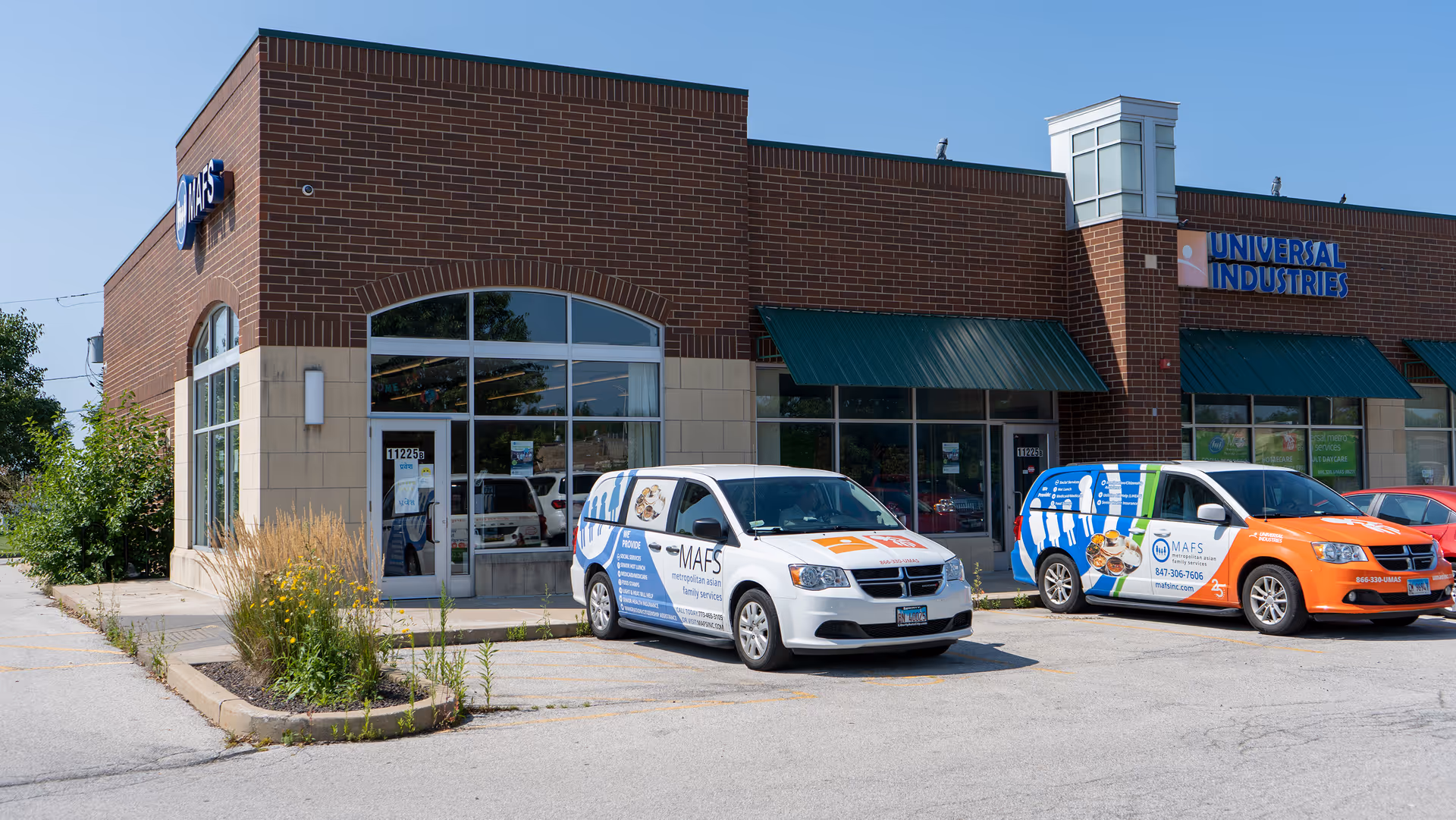 Brick storefront with arched window, green awnings, and branded vans outside.