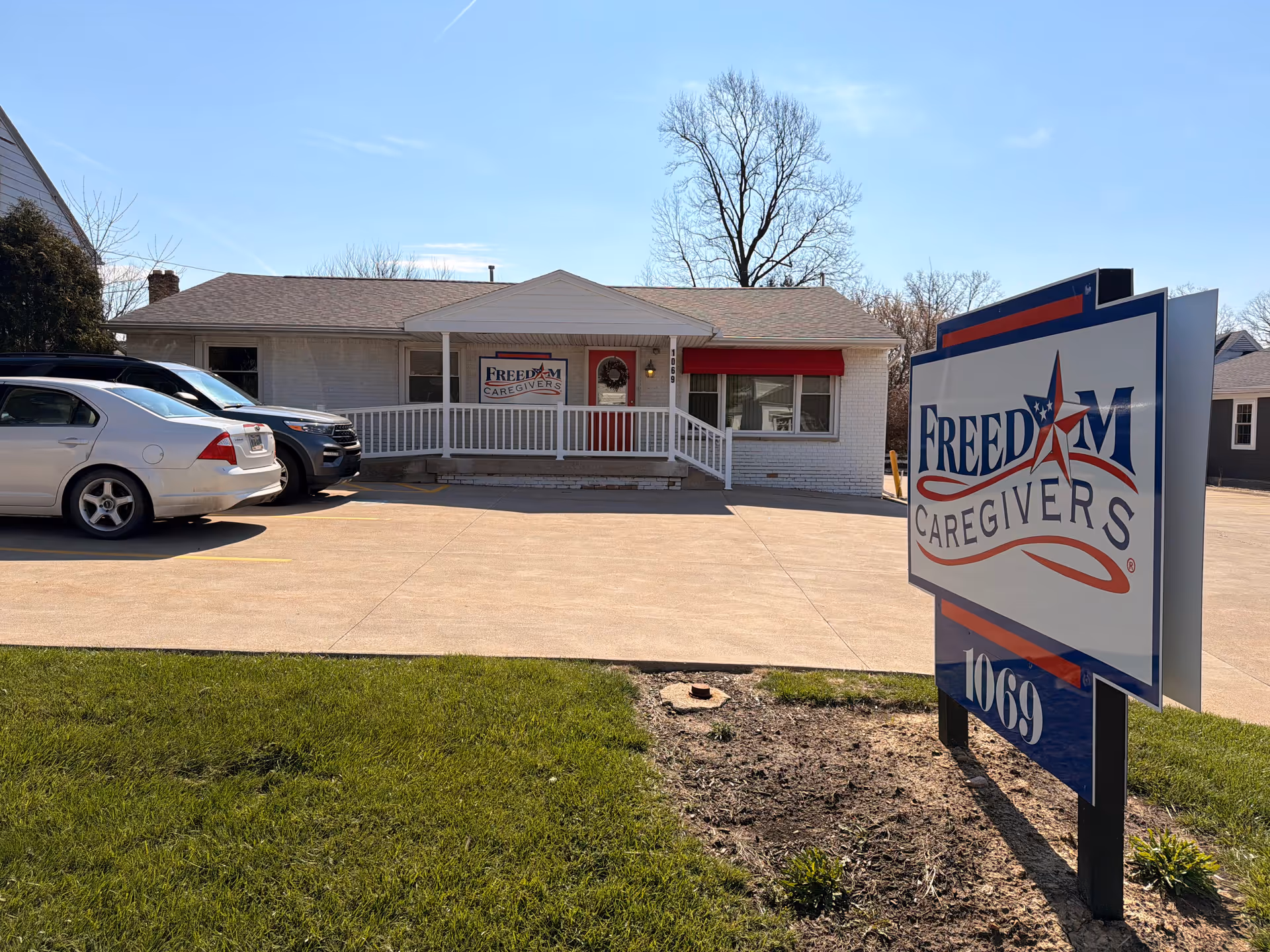 Front view of a single-story white brick building with a large Freedom Caregivers sign.