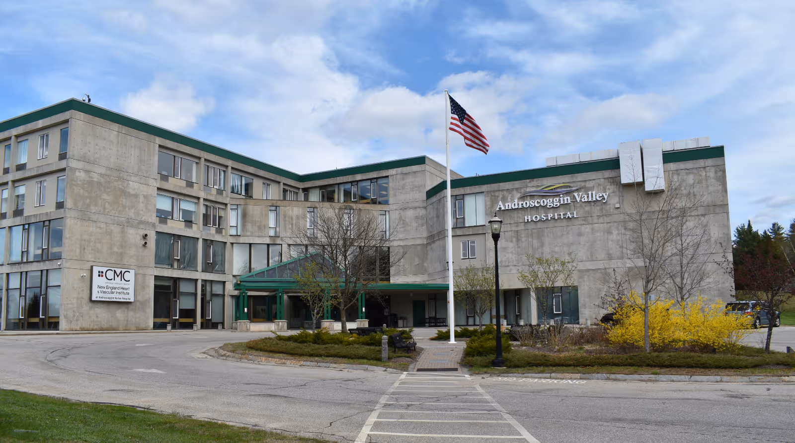Exterior view of Androscoggin Valley Hospital building with flag and landscaping.
