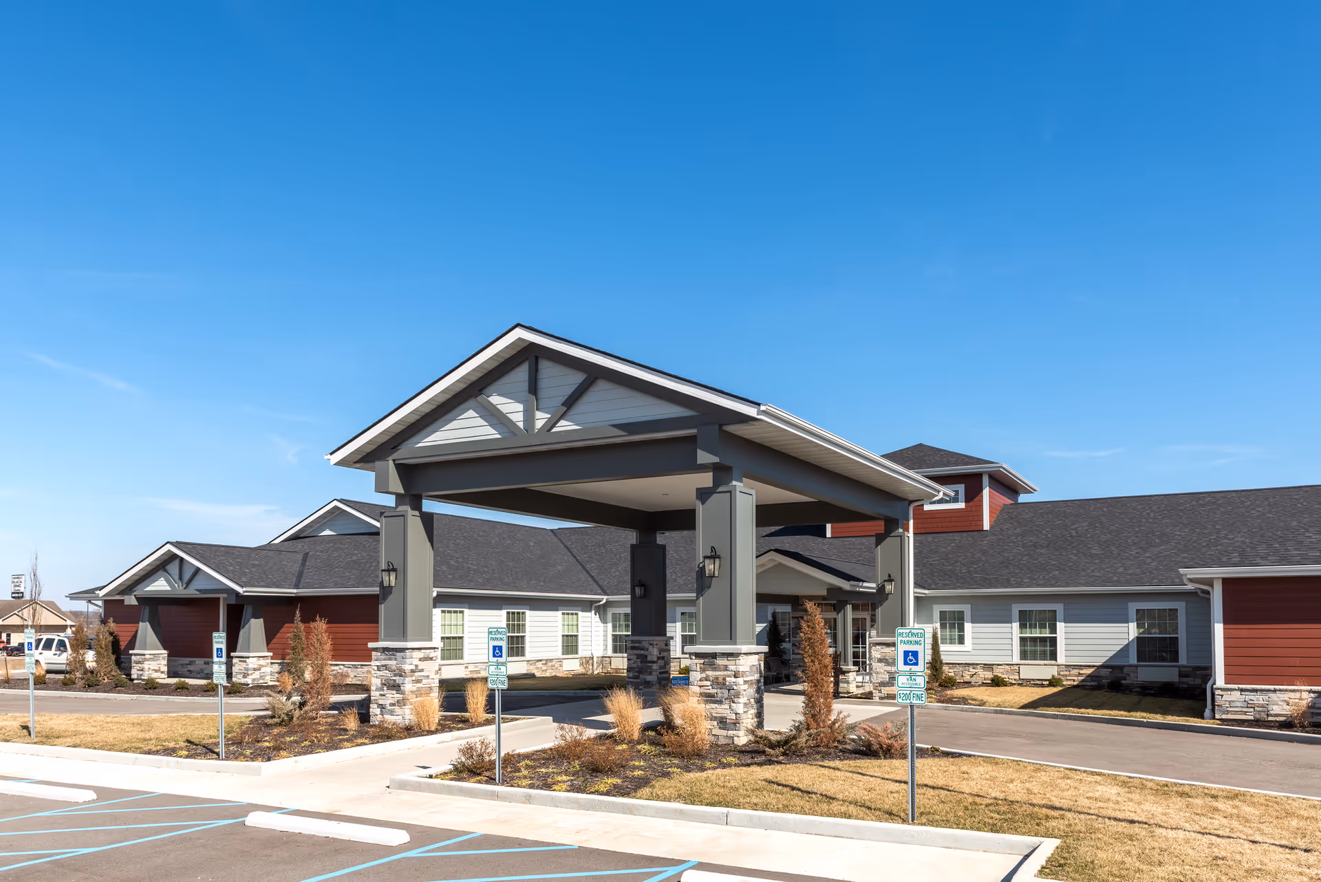 Front view of Provision Living at Livonia featuring a covered entrance and parking area.