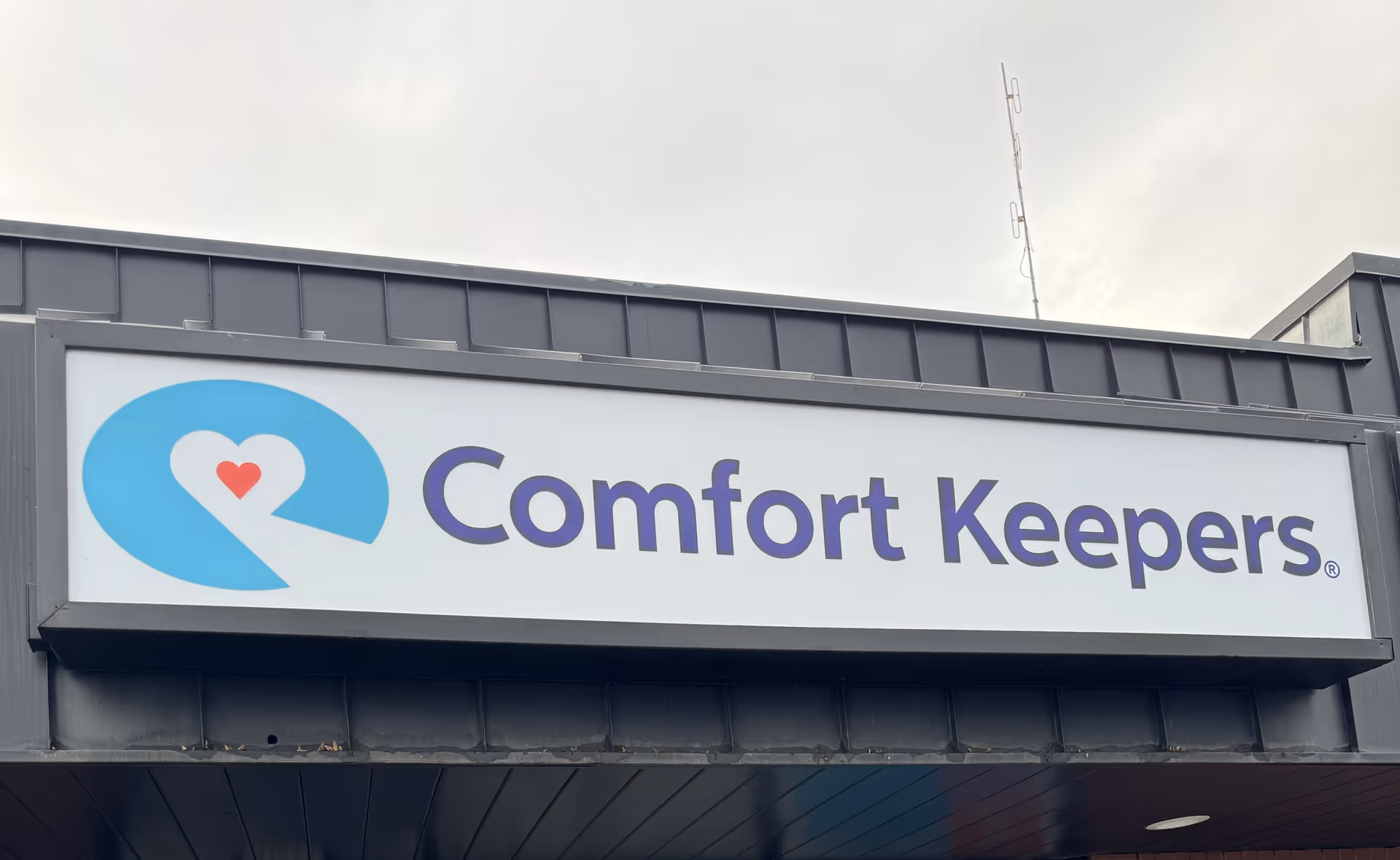 Exterior building sign reading Comfort Keepers with a blue logo