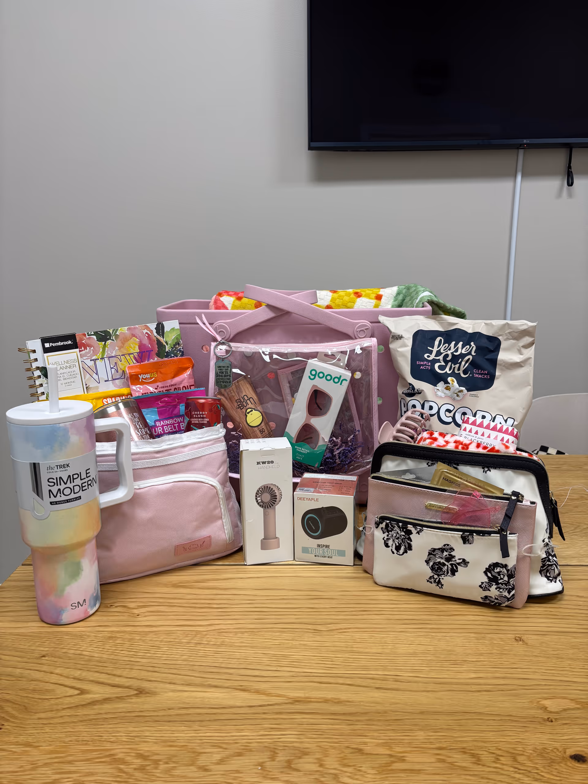 Assorted gift bags and care items arranged on a wooden table in a room.