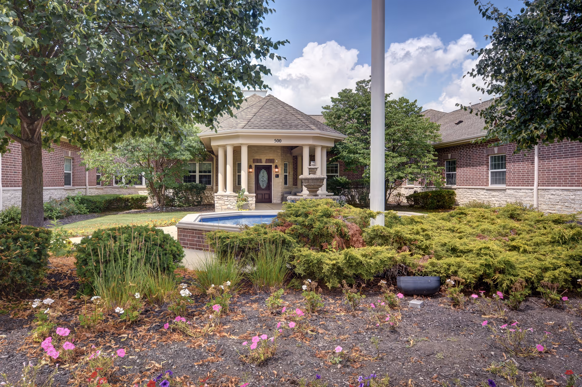 Aspen Woods Memory Care of Vernon Hills entrance with landscaped courtyard and fountain.