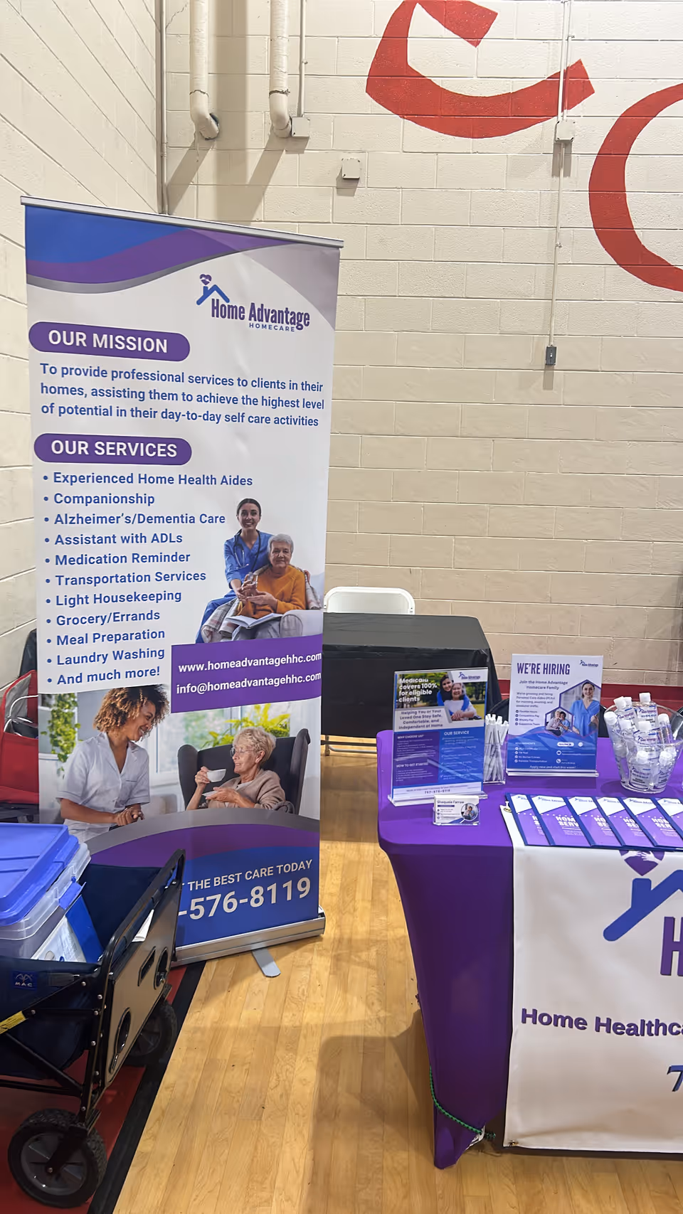 Indoor event booth featuring banners and a purple table promoting Home Advantage Homecare services.