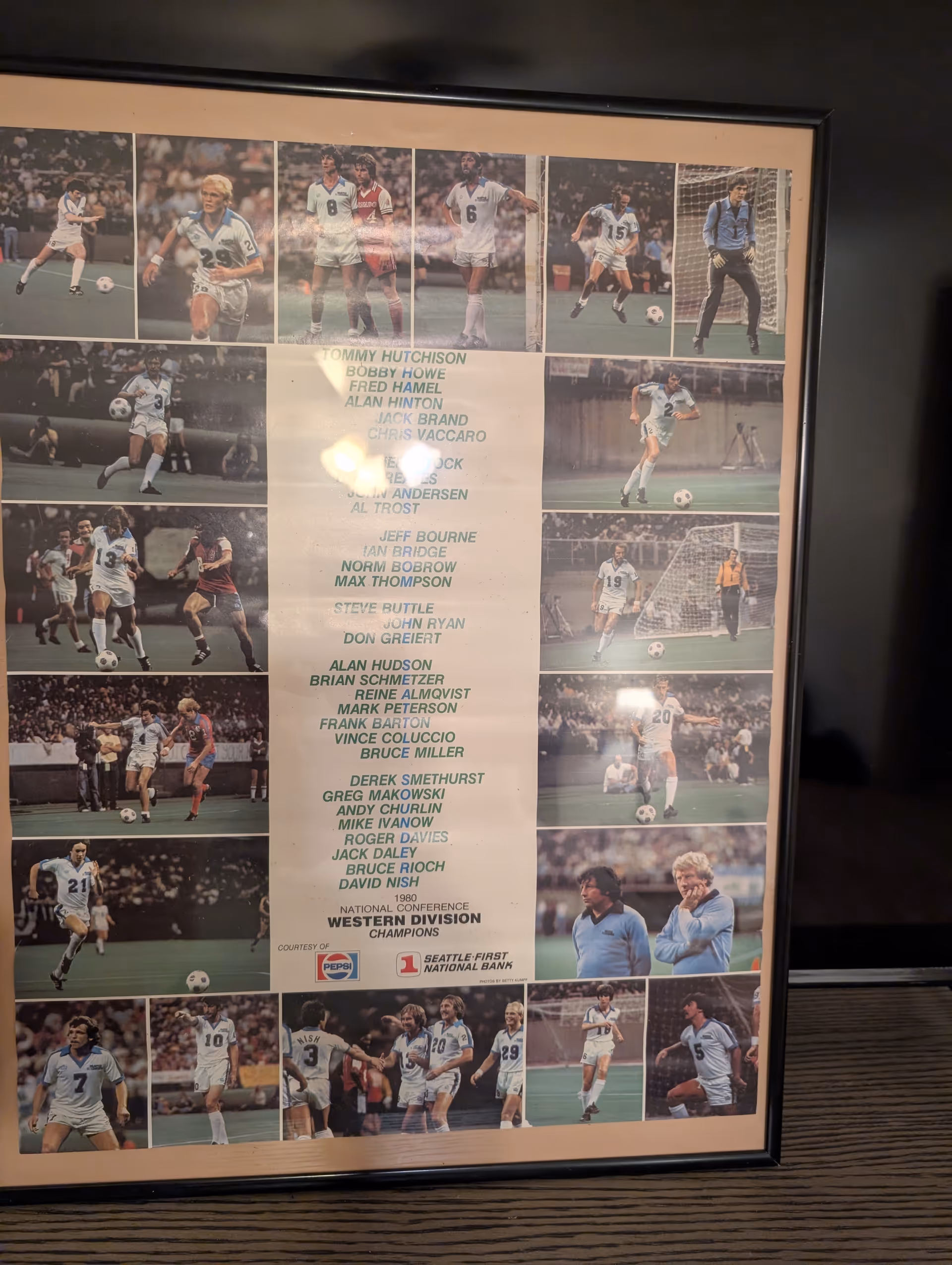 Framed collage of soccer players on a wall inside a facility.