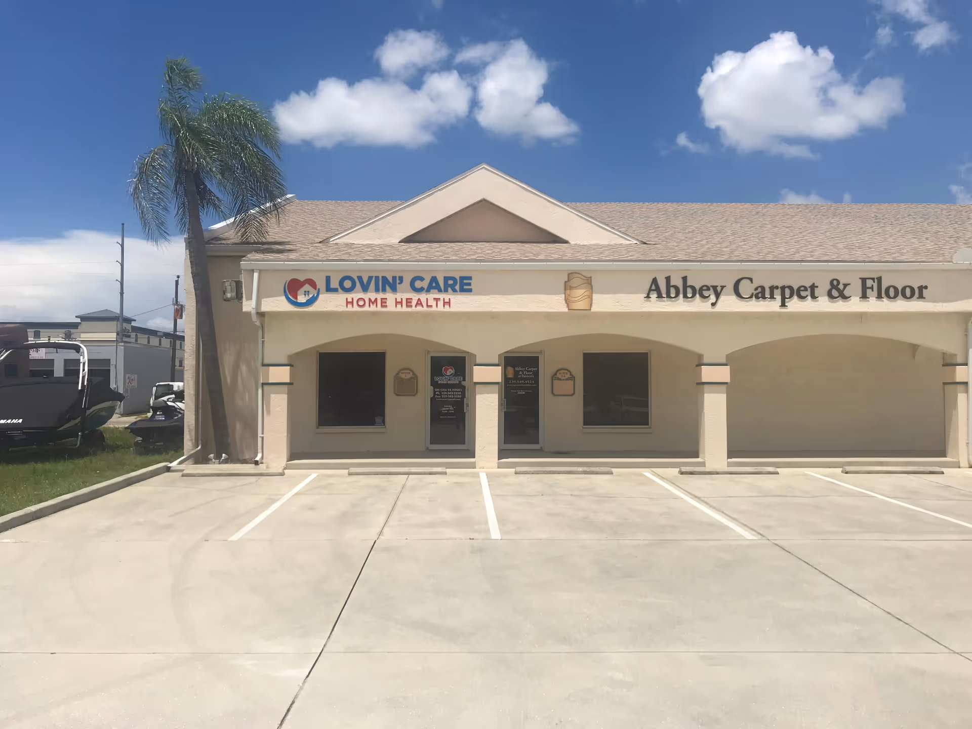 Front of a beige storefront with Lovin' Care Home Health and Abbey Carpet & Floor signs.