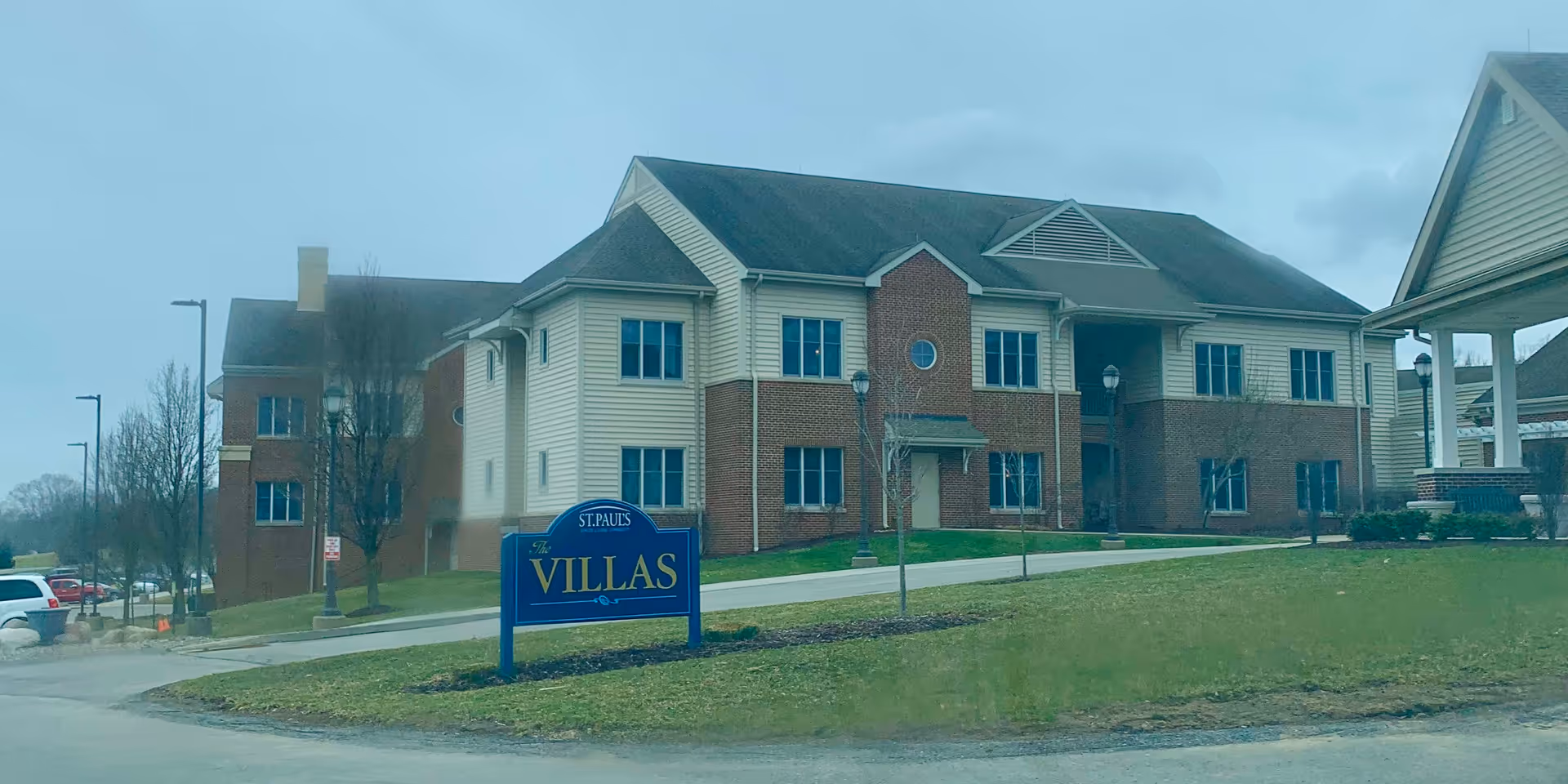 Exterior view of a brick and siding senior living building with a blue villas sign.