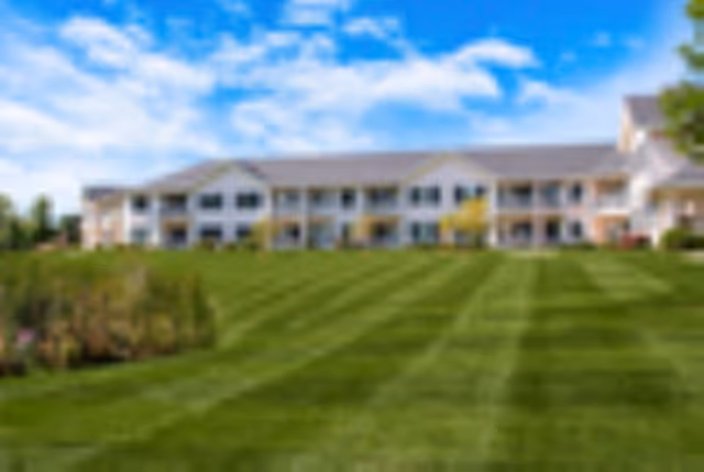 Blurred exterior view of Spaulding House with green lawn and blue sky.