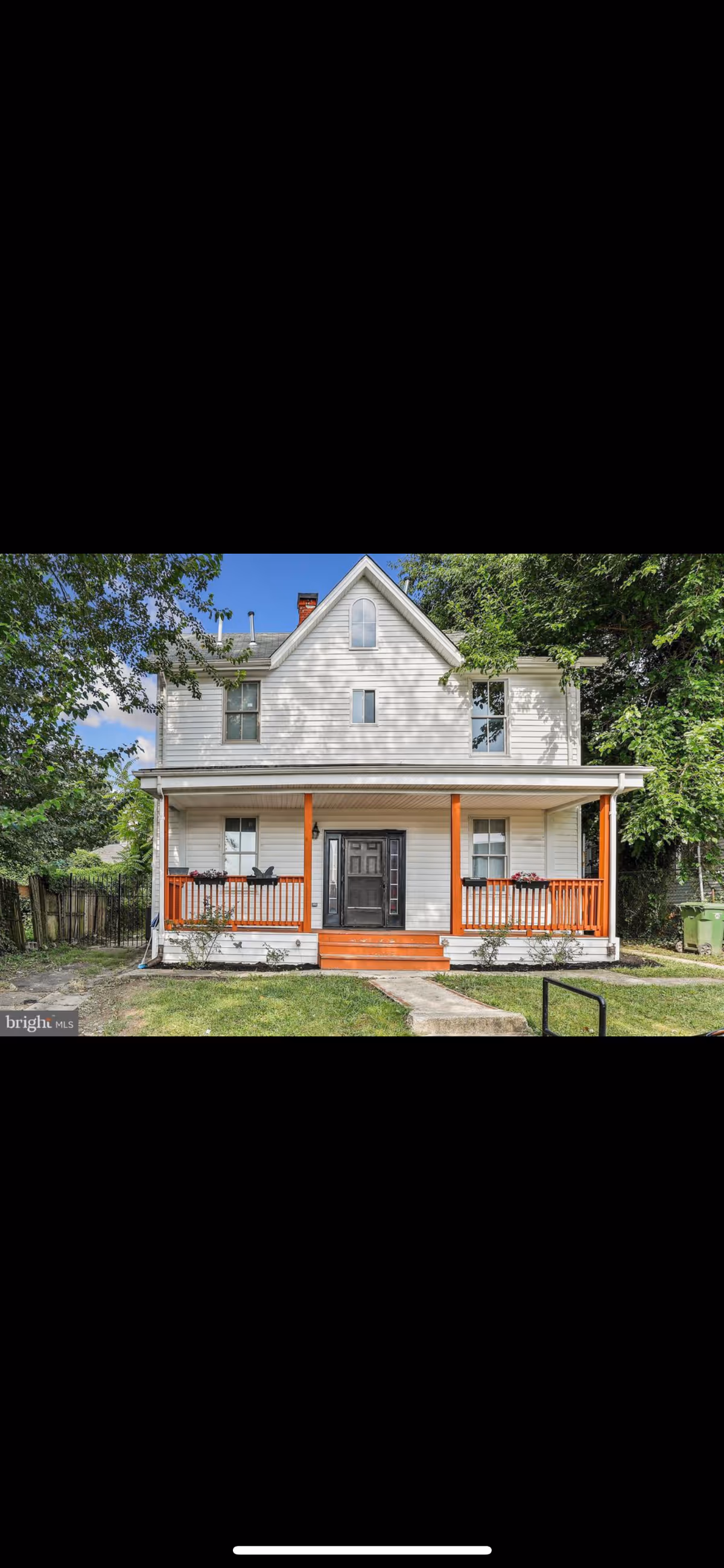 White two-story house with orange porch columns and a small front yard.
