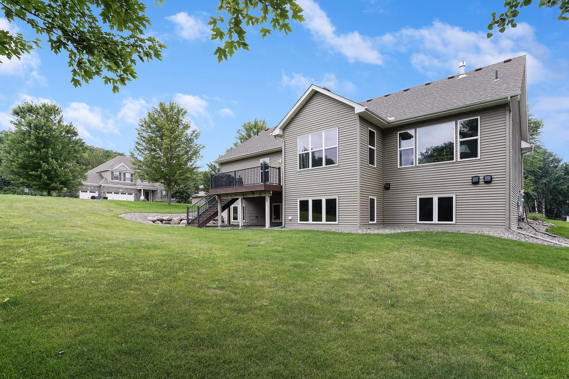 Two-story beige assisted living facility with a grassy lawn and trees.