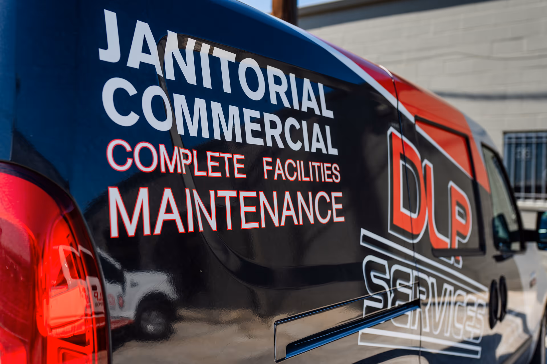 Side of a DLP Services maintenance van with bold white lettering.