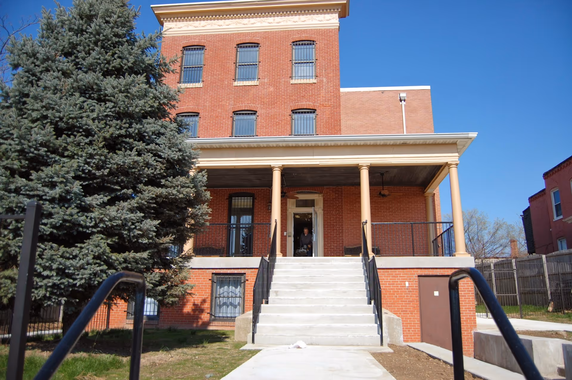 Brick, multi-story senior living facility with a wide staircase and covered entrance.