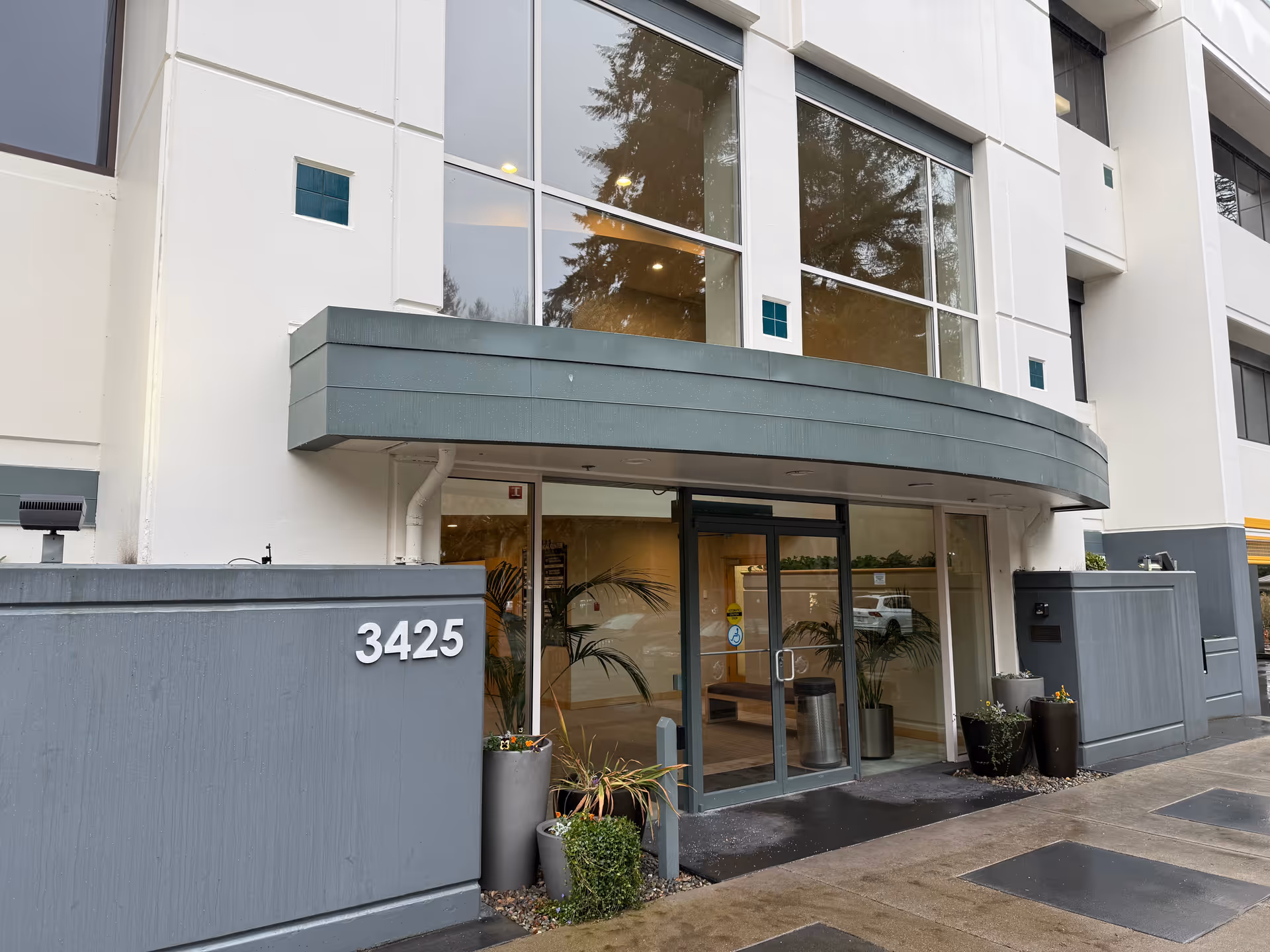 Modern senior living facility exterior with curved canopy, glass doors, and address 3425.