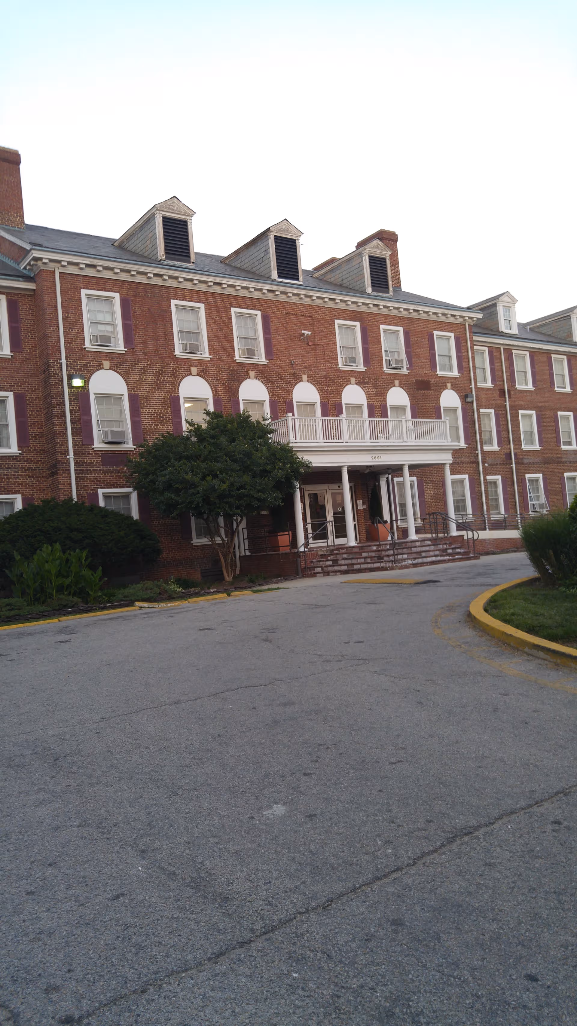 Brick senior living facility facade with arched windows and central entrance.