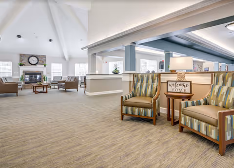 Bright senior living lobby with comfortable seating, a reception desk, and a fireplace.