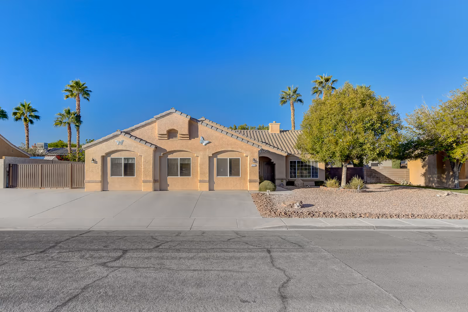 Monarch Group Home exterior, single-story beige building with palm trees and desert landscaping.