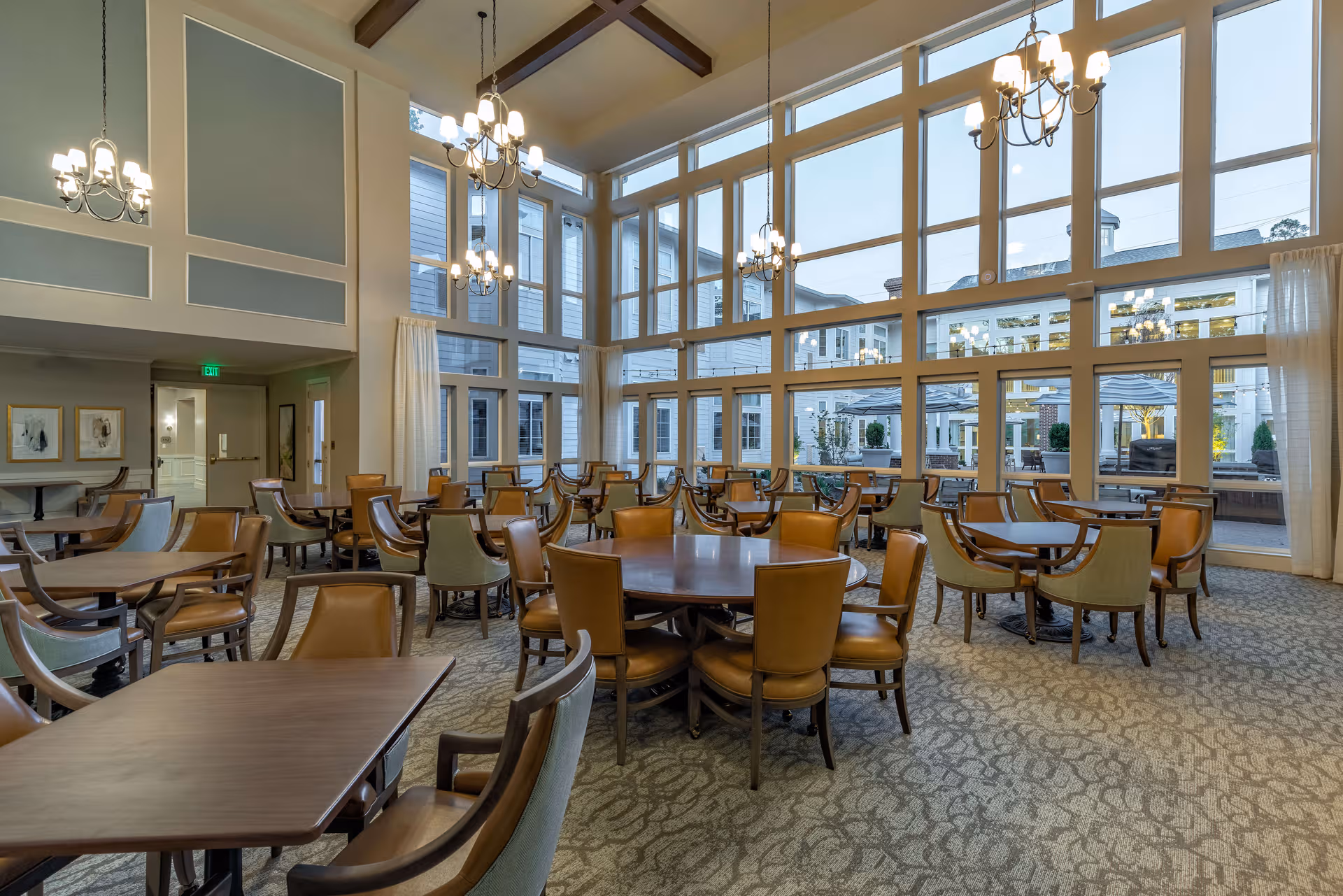 Bright senior living dining room with multiple tables and large windows.