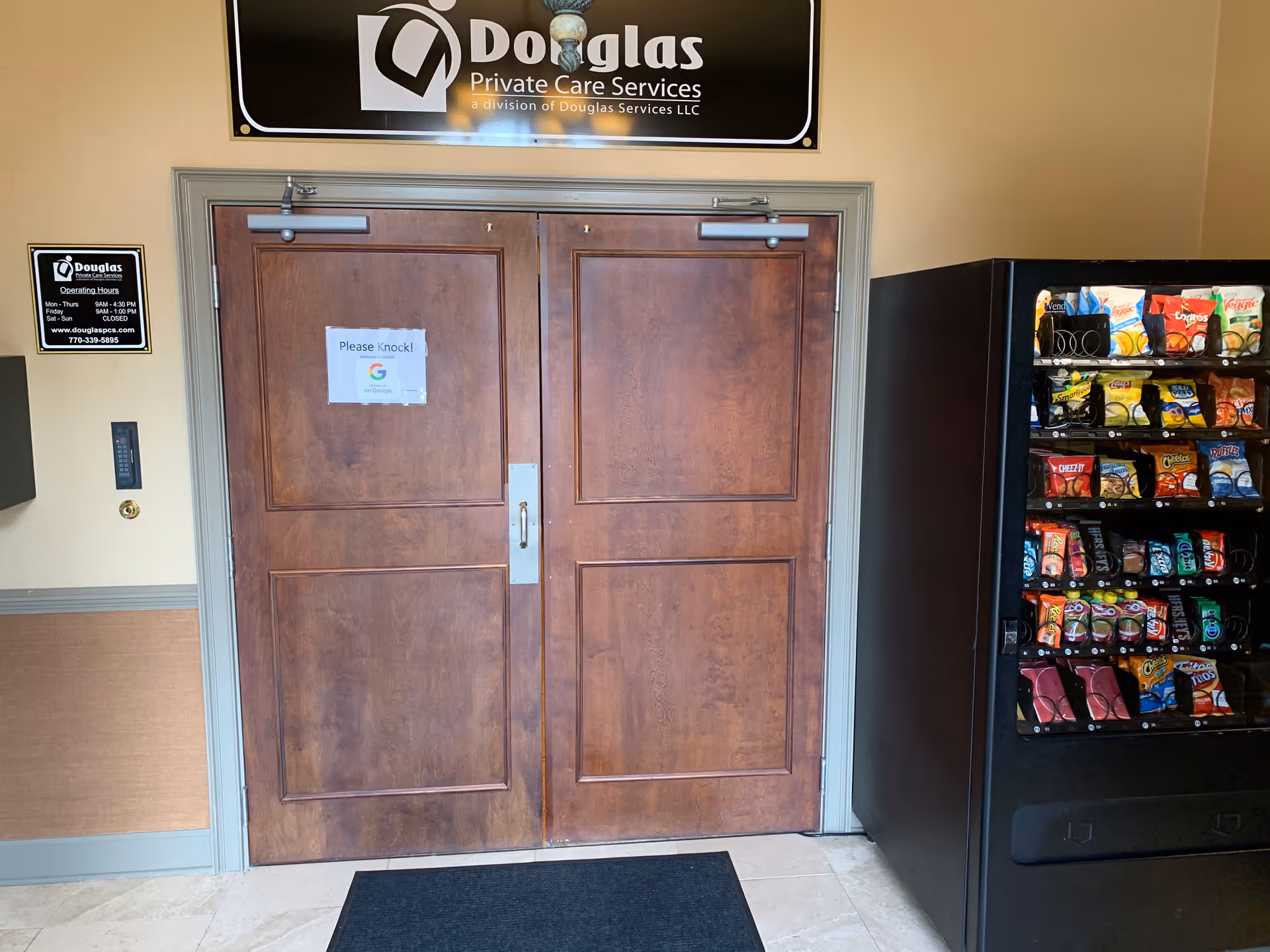 Double wooden doors in a hallway with a vending machine to the right.