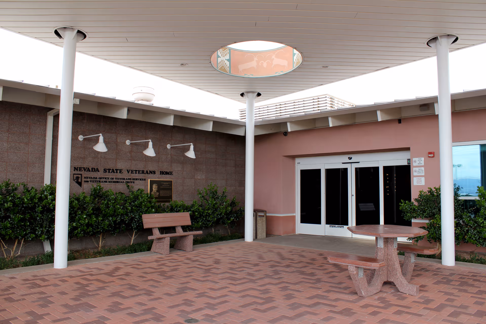Exterior entrance of Nevada State Veterans Home with benches and canopied walkway.