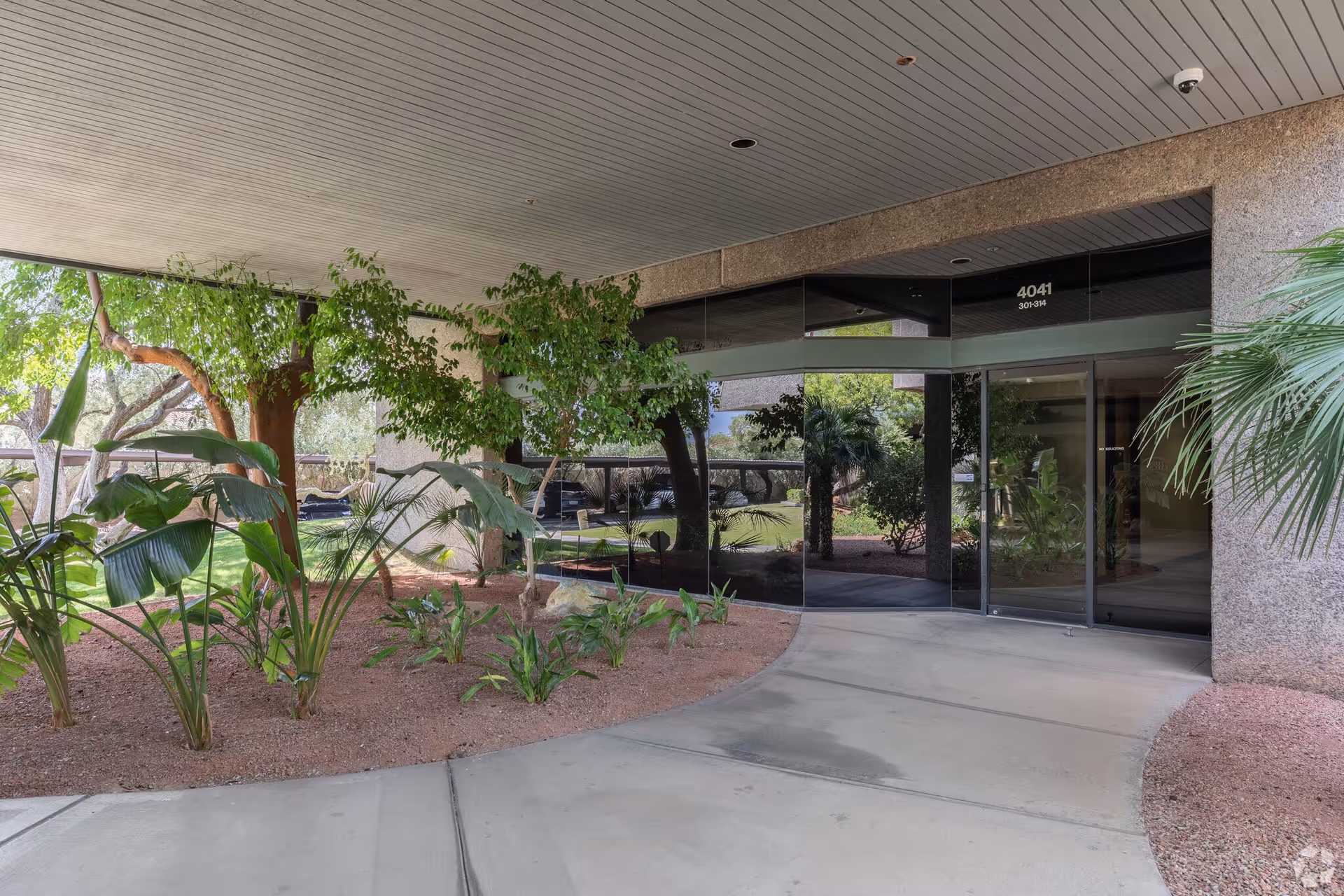 Exterior entrance of Granny NANNIES Home Care with glass doors and landscaped plants.