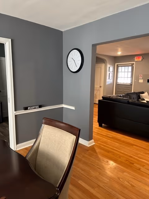 Interior of Stewart Manor common area with clock, coffee sign, and couch.