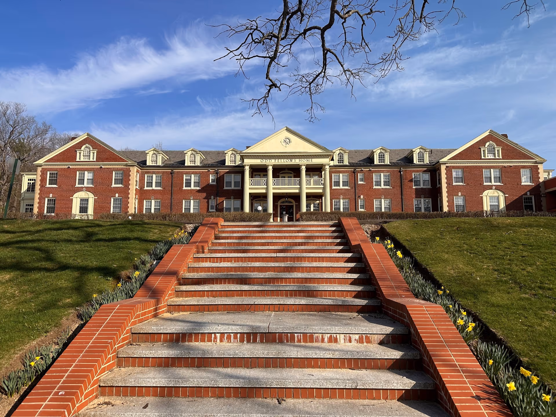 Front exterior of Presidential Oaks I, a brick senior-living building with a central stairway.