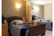 Two single beds with matching nightstands and a divider curtain in a shared bedroom.