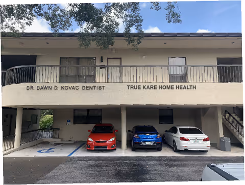 Three cars parked under a covered building entrance with True Kare Home Health sign.