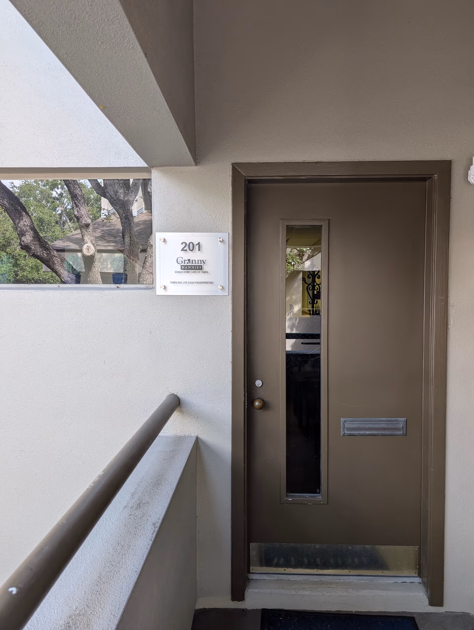Exterior entrance of a senior home with a door, railing, and Granny Nannies sign.