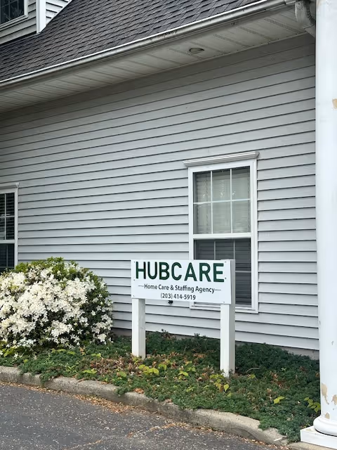 Exterior view of a gray building with a Hubcare sign and surrounding shrubs.