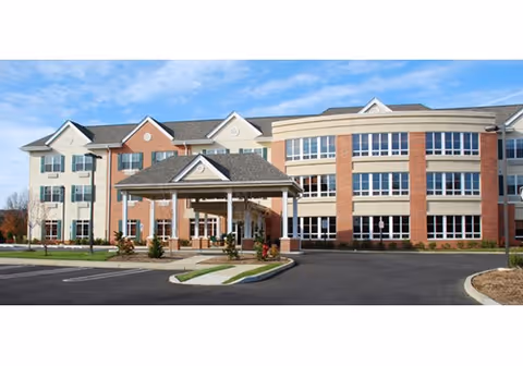Exterior view of a brick nursing home with entrance canopy and parking.
