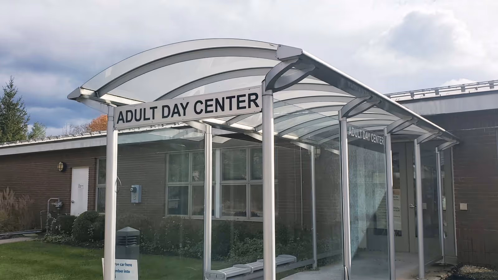 Exterior view of an Adult Day Center entrance with a curved glass canopy.